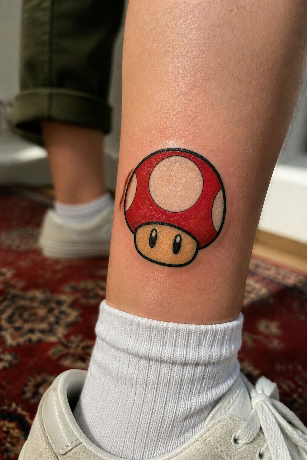 Mario mushroom tattoo with a red cap and white dots.