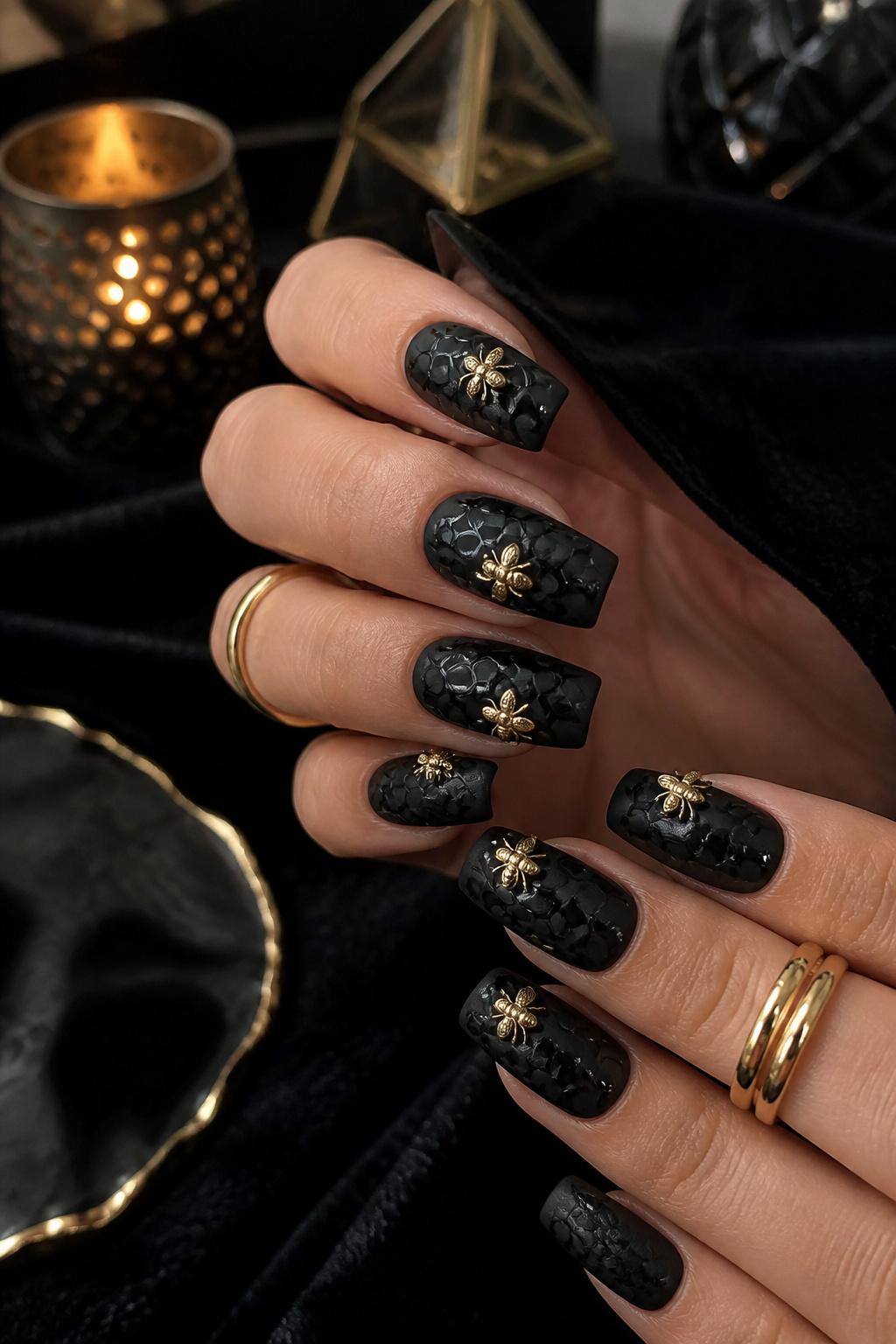 Matte black nails featuring glossy honeycomb designs and shiny gold bees.