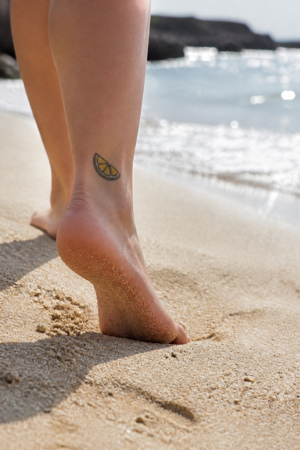 Lemon Tattoo Designs, Meanings, Styles & 2026 Placement Guide 5 A lemon wedge tattoo on an ankle, showcasing its yellow interior and rind.