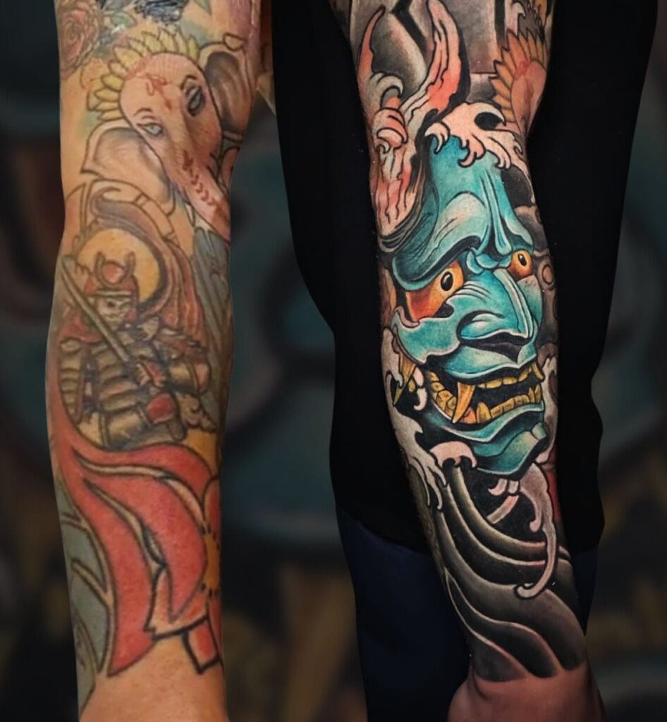 Two arms displaying large, colorful Japanese-style tattoos including a Ganesha and a blue Hannya mask.
