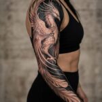 A large black and grey phoenix tattoo covering a person's entire arm.