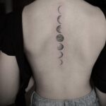 A vertical moon phases tattoo design running down a person's spine.