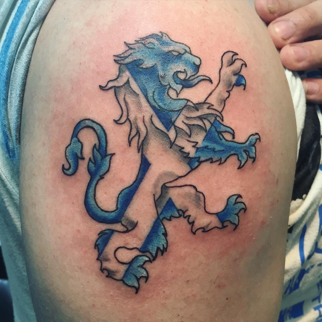 A lion rampant tattoo with blue and white Saltire stripes on a person's shoulder.