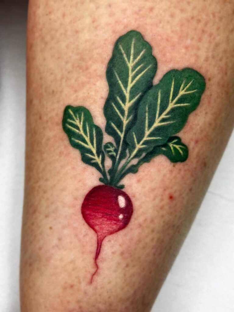 A vibrant radish tattoo with a red bulb and green leaves on skin.